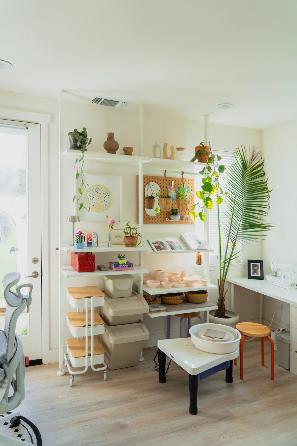 A bright pottery studio with a wheel and shelves of ceramics